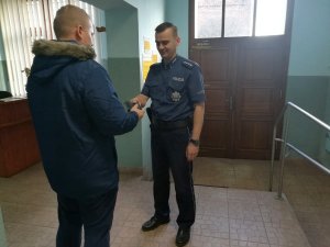 Pomieszczenie recepcji w Komendzie Powiatowej Policji w Żninie. Policjant przekazuje portfel mężczyźnie, który go zgubił.