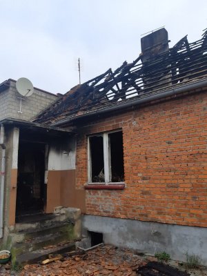Widok spalonego mieszkania z zewnątrz. Na zdjęciu widoczne belki stropowe. Brak pokrycia dachówkami.