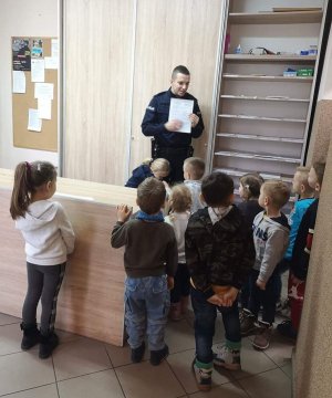 Sierż. szt. Michał Tylak prezentuje dzieciom jak wygląda protokół i tłumaczy jakie dane należy w nim zawrzeć.
