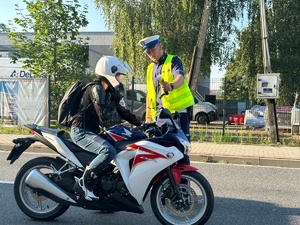 Kontrola trzeźwości motocyklisty. Z lewej strony mężczyzna siedzi na motocyklu. z prawej strony policjant ruchu drogowego, który okazuje mu wynik na alkomacie.
