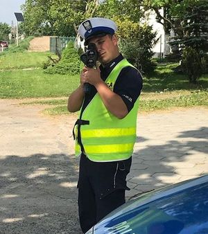 policjant  przy użyciu ręcznego miernika prędkości dokonuje  pomiaru prędkości pojazdu
