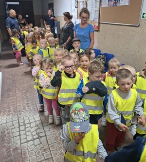 grupa dzieci wraz opiekunkami  i policjantami czeka na korytarzu