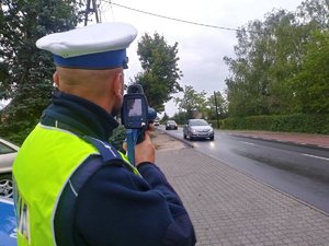 Policjant ruchu drogowego wykonuje pomiar prędkości przy użyciu laserowego miernika