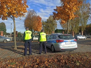 Policjanci w żółtych kamizelkach obserwują ruch samochodów.