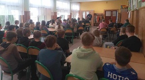 Zajęcia profilaktyczne w Szkole Podstawowej w Rogowie. Policjant opowiada o czynach karalnych. Przed nim siedzi młodzież.